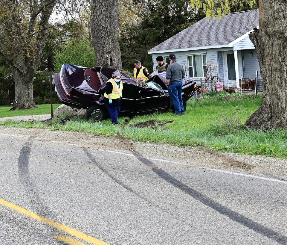 Deputies and an observer look over the crashed vehicle on Jonesville Road sunday afternoon.