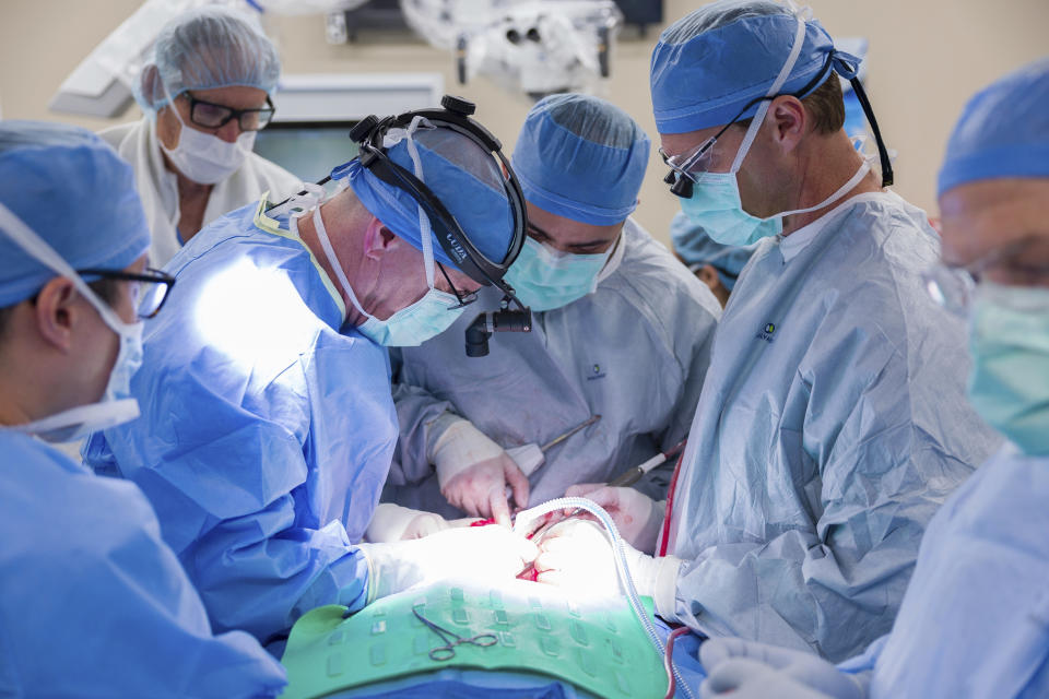 In this photo provided by the Mayo Clinic, Dr. Michael Hinni, center left, Dr. Payam Entezami, center, and Dr. David Lott, center right, operate on transplant patient Marty Kedian in Phoenix, Feb. 29, 2024. Kedian regained his voice after surgeons removed his cancerous larynx and, in a pioneering move, immediately replaced it with a donated one. (Mayo Clinic via AP)