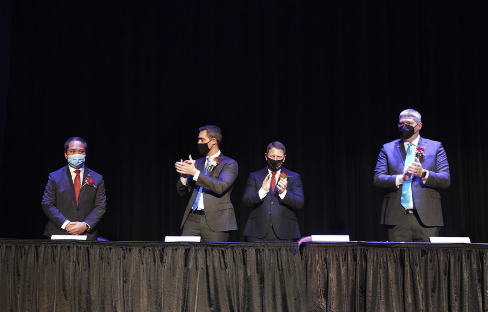 In this photo provided by Peg Shanahan, new Mayor Sokhary Chau, left, is applauded by councillors John Drinkwater, second from left, vice chair Erik Gitschier and Wayne Jenness during the Lowell City Council swearing-in ceremony, Monday, Jan. 3, 2022, in Lowell, Mass. Chau, a refugee who survived the Khmer Rouge’s bloody regime, has become the city’s first mayor of color and the first Cambodian American mayor in the United States. (Peg Shanahan via AP)