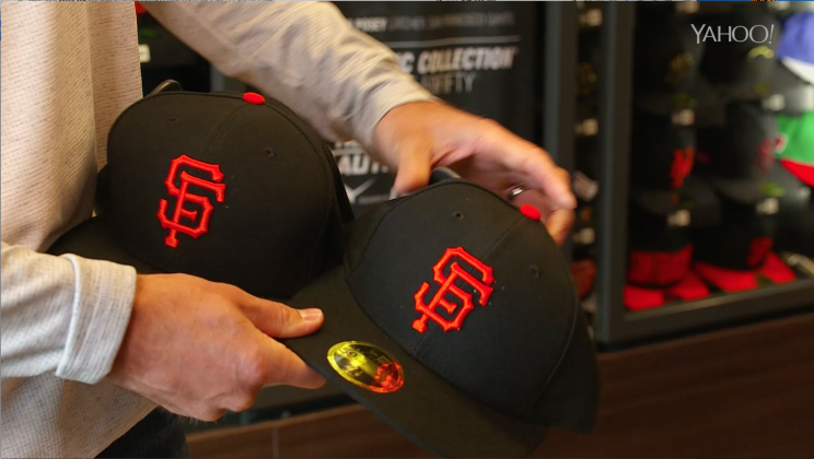 Buster Posey shows the difference in the low-profile New Era cap and the regular one. (Yahoo Sports)