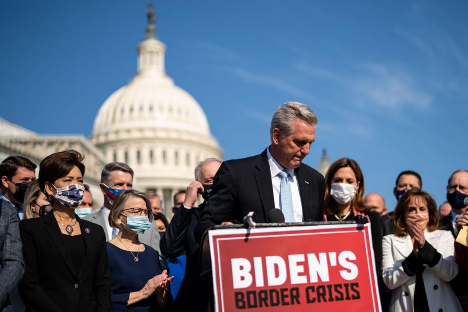 People stand behind a lectern with the U.S. Capitol in the background.