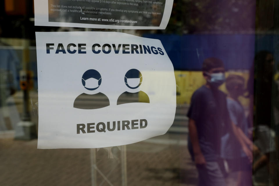 A visitor wearing a mask to protect against the spread of COVID-19 passes a sign requiring masks in San Antonio, Texas. (Photo: ASSOCIATED PRESS)