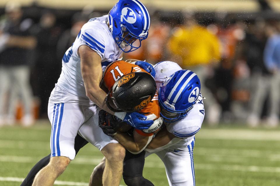 BYU safety Talan Alfrey, left, and linebacker Ace Kaufusi tackle Oklahoma State wide receiver Leon Johnson III (17) during the second half of an NCAA college football game Saturday, Nov. 25, 2023, in Stillwater, Okla. | Mitch Alcala, Associated Press