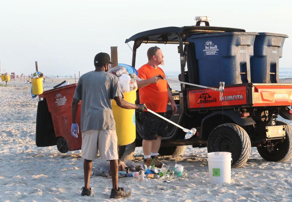 Crew members of CFB Outdoors pick up trash in front of the Daytona Beach Boardwalk on the day after July 4th celebrations in 2022.  The post-July 4th cleanup is the biggest beach-related job that the company has all year, said owner Ben Hester.
