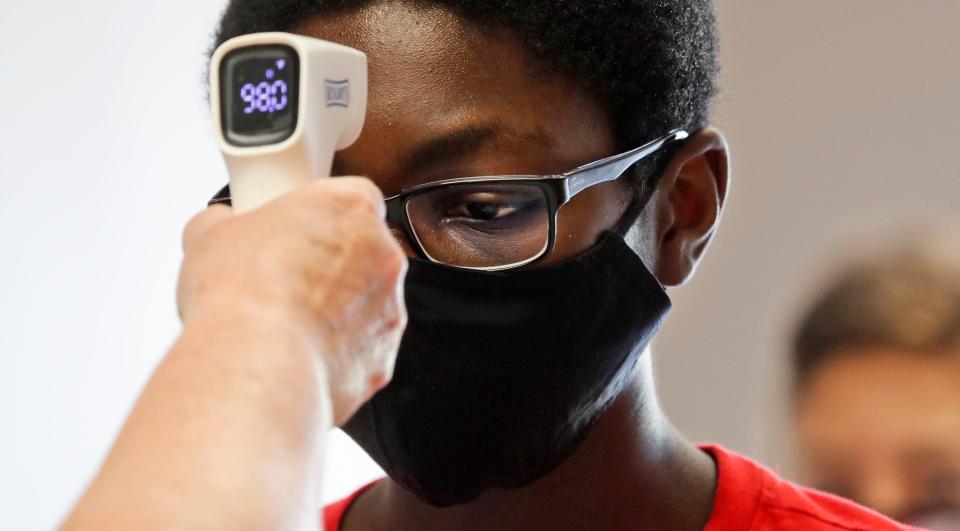 A student gets his temperature checked by a teacher before entering a summer STEM camp at Wylie High School in Texas. Schools across the USA continue to plan on how to reopen schools this fall.