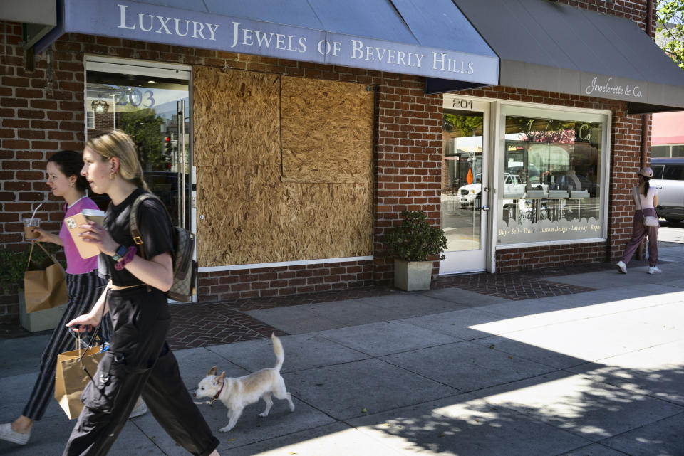 Shoppers walk past a boarded up Luxury Jewels of Beverly Hills on Wednesday, March 23, 2022 in Beverly Hills, Calif. Los Angeles police are warning people that wearing expensive jewelry in public could make them a target for thieves — a note of caution as robberies are up citywide. The police department's suggestion Tuesday, March 22, came as robbers smashed the front window of a Beverly Hills jewelry store in broad daylight and fled with millions of dollars' worth of merchandise. (AP Photo/Richard Vogel)