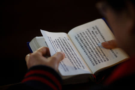 FILE PHOTO: A believer reads the bible during mass at St. Joseph's Church, a government-sanctioned Catholic church, in Beijing, China, October 1, 2018. REUTERS/Thomas Peter/File Photo