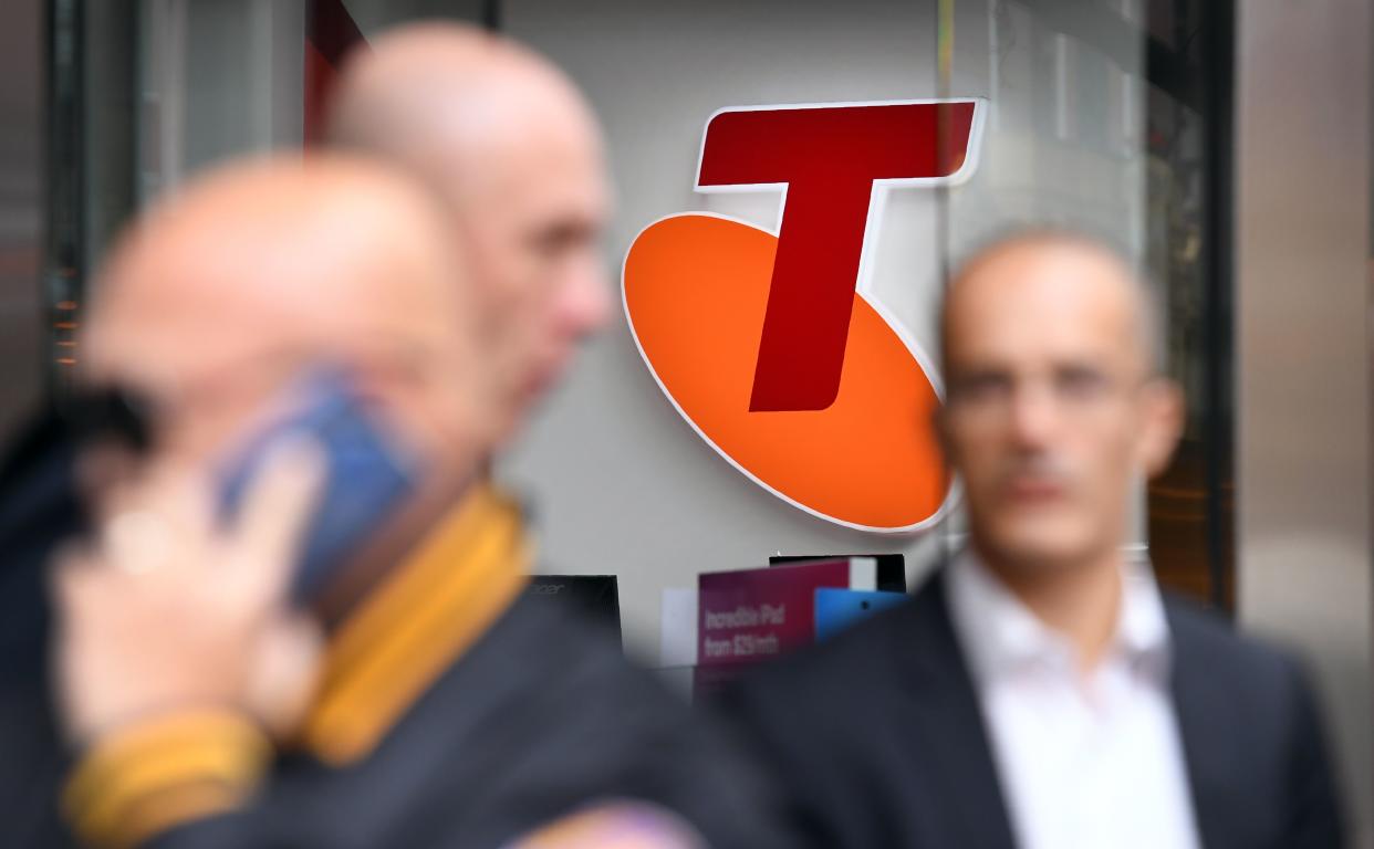 People walk past a sign of telecommunications company Telstra in Melbourne on August 16, 2018. - Australia's dominant telecommunications company Telstra on August 16 warned of "enormous challenges" ahead as it posted an 8.9 percent slump in annual profit. (Photo by William WEST / AFP)        (Photo credit should read WILLIAM WEST/AFP via Getty Images)