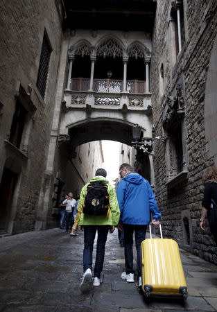 A couple walks by Carrer del Bisbe at Gothic quarter with their baggage in Barcelona, Spain, August 18, 2015. REUTERS/Albert Gea