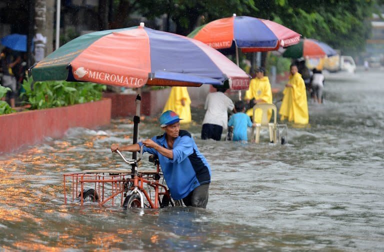 A pedicab driver wades through a flooded street in Manila on August 19, 2013 after heavy rain hit the Philippine capital. At least three people have died in the Philippines after torrential rain engulfed parts of the main island of Luzon including Manila where neck-deep water swept through homes forcing thousands into emergency shelters