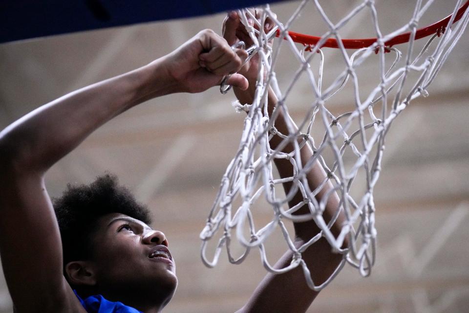 Ready’s Darrius Goins cuts off a piece of the net during the team's CCL championship celebration after defeating visiting St. Charles 59-40 Friday night.