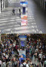 A combo of images shows people milling around at St Pancras International train station, in London on Friday, July 26, 2019 and the empty scene taken from the same angle on Thursday, April 2, 2020. When Associated Press photographer Frank Augstein moved to London in 2015, what struck him most was the crowds. Augstein revisited in recent days many of sites he has photographed, after Britain — like other countries around the world — went into effective lockdown to stem the spread of the new coronavirus. (AP Photo/Frank Augstein)