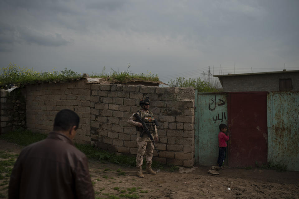 In this April 3, 2019 photo, an Iraqi army 20th division soldier waits outside a house during a patrol in the Badoush, Iraq area. A year and a half after the Islamic State group was declared defeated in Iraq, efforts to find remnants rely on intelligence operations, raids and searches for sleeper cells among the population. (AP Photo/Felipe Dana)