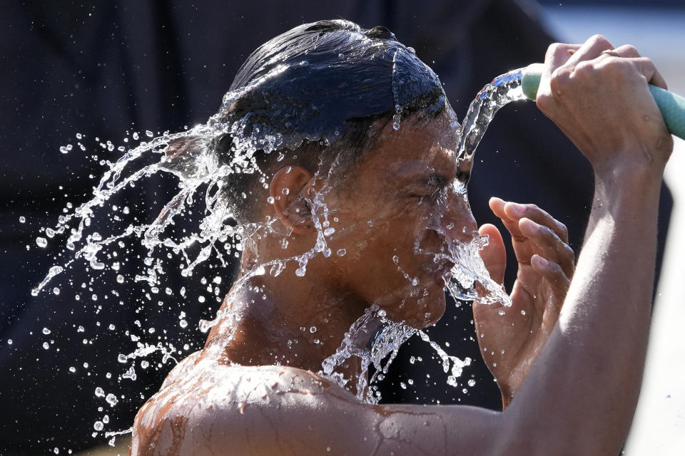 A man pours water from a pipe over himself on a hot day in Manila, Philippines, Friday, April 26, 2024. (AP Photo/Aaron Favila)