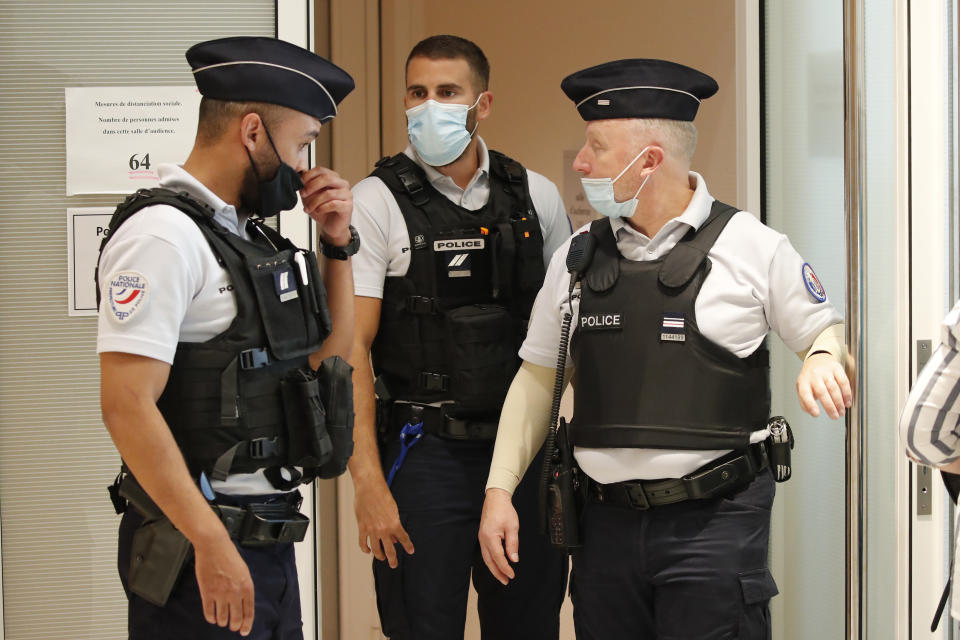Police officers secure one of the entrances of courtroom during the opening of the 2015 attacks trial, Wednesday, Sept. 2, 2020 in Paris. Thirteen men and a woman go on trial Wednesday over the 2015 attacks against a satirical newspaper and a kosher supermarket in Paris that marked the beginning of a wave of violence by the Islamic State group in Europe. Seventeen people and all three gunmen died during the three days of attacks in January 2015. (AP Photo/Francois Mori)