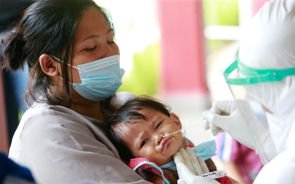 A 1-year-old infant, reacts as a healthcare worker takes a swab sample to test for the coronavirus disease during mass testing at a school in Jakarta - Ajeng Dinar Ulfiana/REUTERS