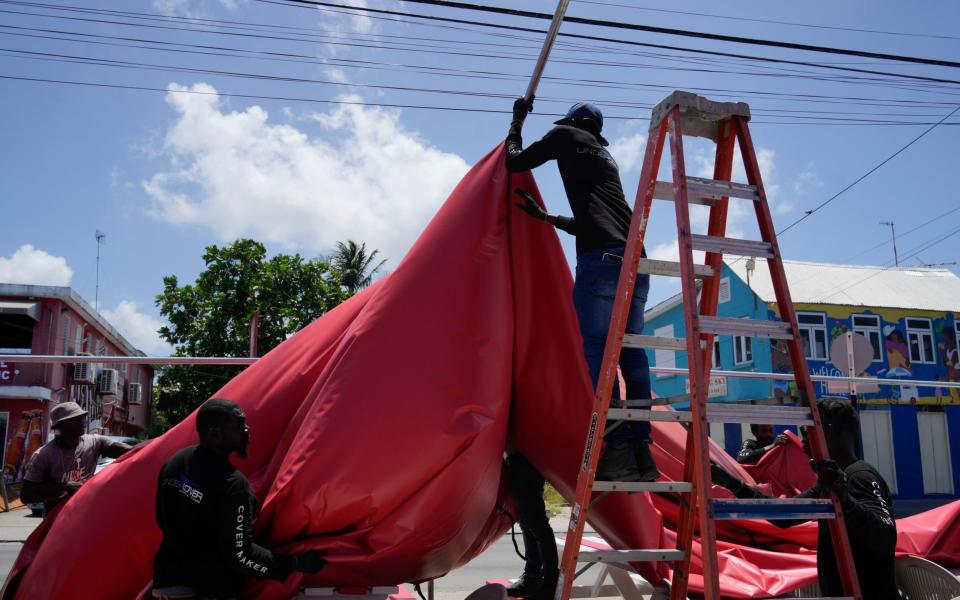 People disassemble a beach bar's awning in preparation for Hurricane Beryl, in Bridgetown, Barbados,