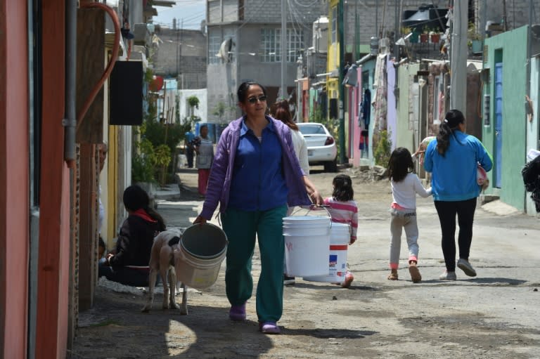 Una mujer carga baldes de agua potable el 19 de abril de 2017 en el barrio de Iztapalapa en Ciudad de México