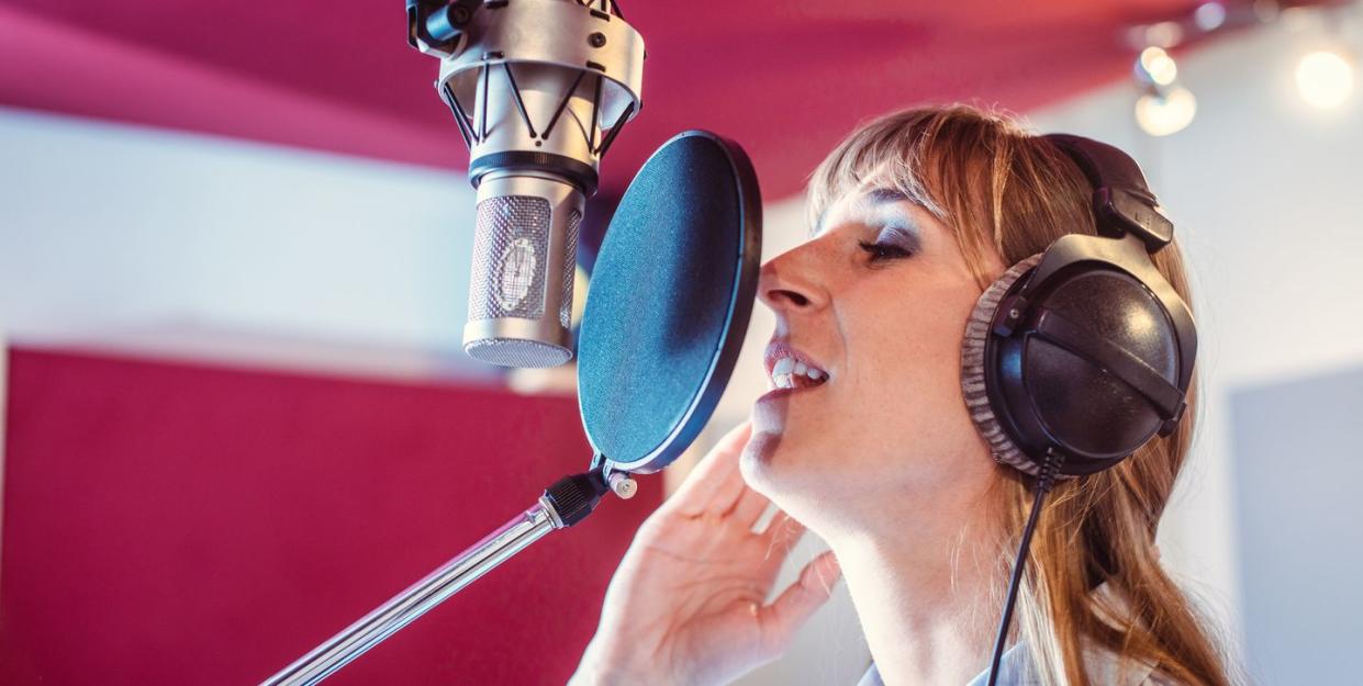 woman singing in microphone at recording studio