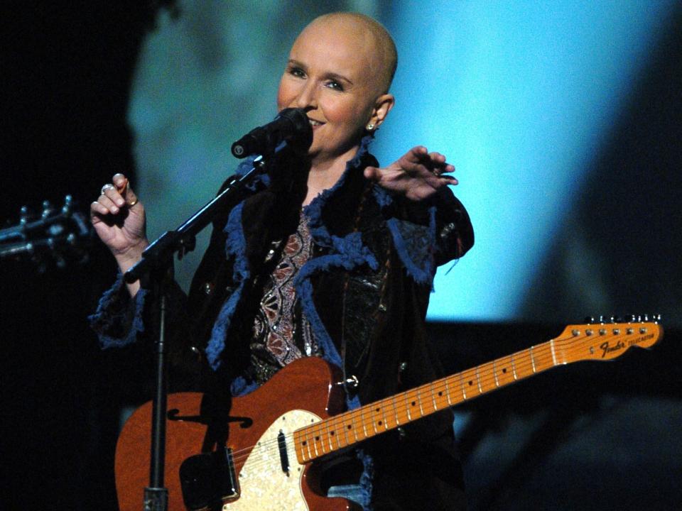 Melissa performing onstage with her guitar while bald from the chemotherapy.