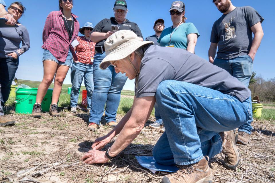 Eileen Kladivko, who was the first woman faculty member in the Purdue agronomy department, shows farmers how to locate and identify worms during a training program.