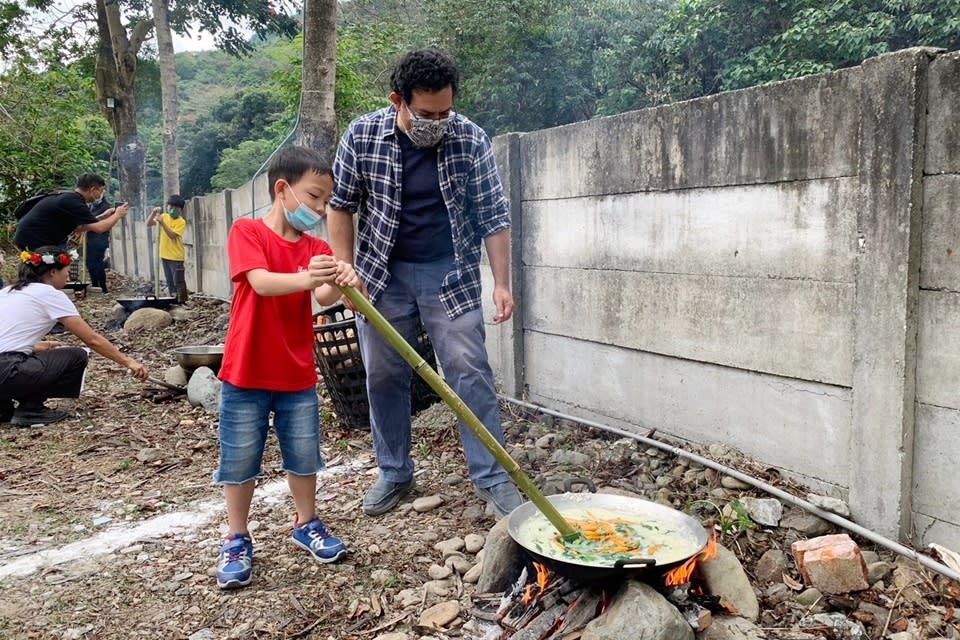 將白米和野菜放入鍋中不斷翻攪，溫泉國小學童體驗製作排灣族傳統美食「搖搖飯」。