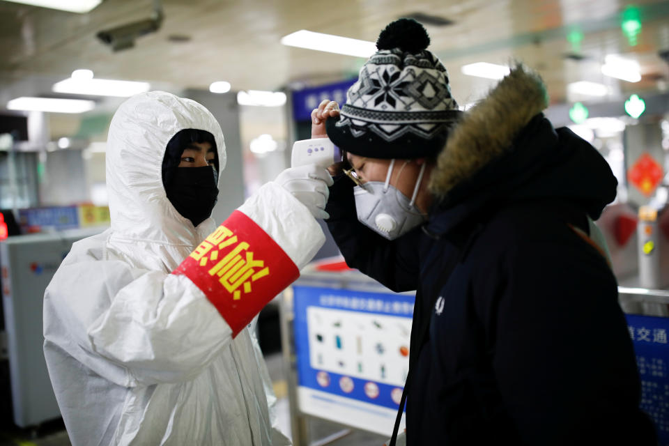 A staff member checks the temperature of a passenger entering a subway station, as the country is hit by an outbreak of the new coronavirus, in Beijing, China January 28, 2020. REUTERS/Carlos Garcia Rawlins