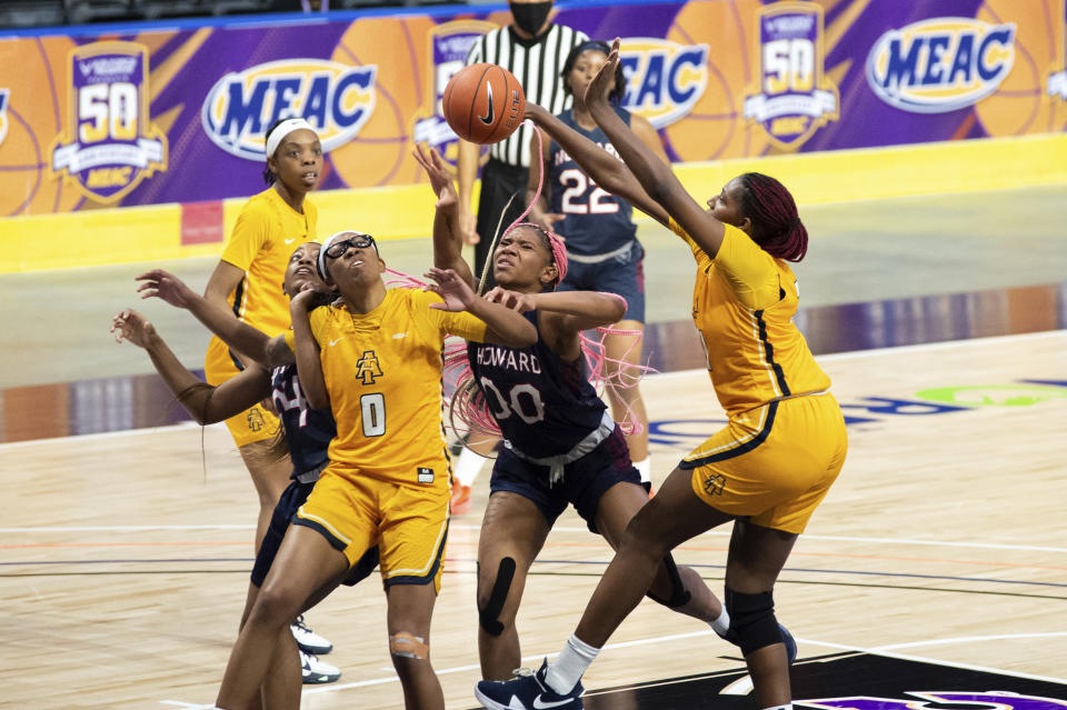 North Carolina A&T's Jayla Jones-Pack, right, knocks the ball out of the hands of Howard's Anzhane' Hutton (00) during the first half of an NCAA college basketball game in the Mid-Eastern Athletic Conference championship Saturday, March 13, 2021, in Norfolk, Va. (AP Photo/Mike Caudill)