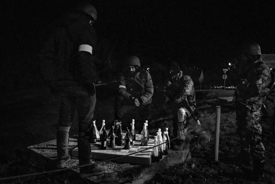 Members the Territorial Defense Forces who guard a large checkpoint briefly played a game of checkers with Molotov cocktails, as seen on the eastern outskirts of Kyiv, Ukraine, on March 5. With few vehicles passing because of the nighttime curfew, Territorial Defense members can have a moment of quiet while remaining on high alert for any suspicious activity.<span class="copyright">Nicole Tung for Harper’s Magazine</span>