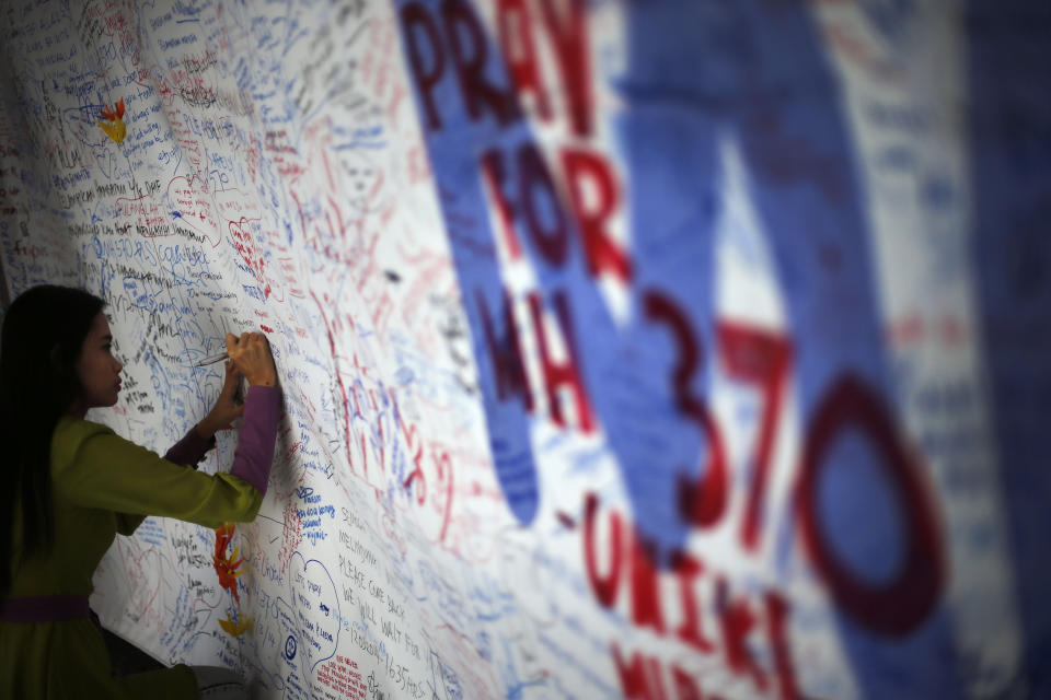 Una mujer escribe un mensaje dedicado a las 239 personas que iban a bordo del vuelo MH370 de Malaysia Airlines y que desapareció hace una semana, el sábado 15 de marzo de 2014, en Sepang, Malasia. (Foto AP/Wong Maye-E)