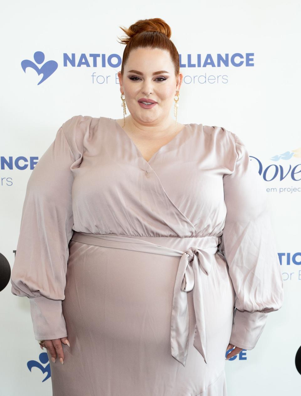 Close-up of Tess at a media event in a long-sleeved, belted dress