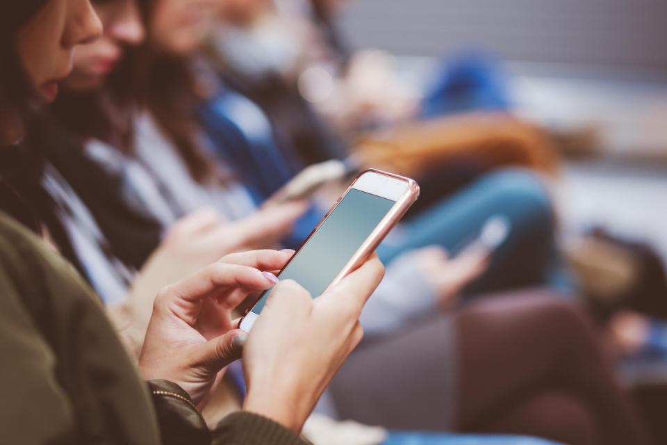 A young woman using her phone in a waiting room, closeup of phone screen