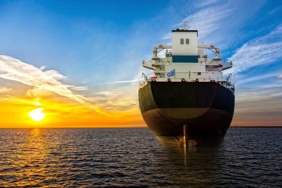 A large ship at sea with the sun setting in the distance