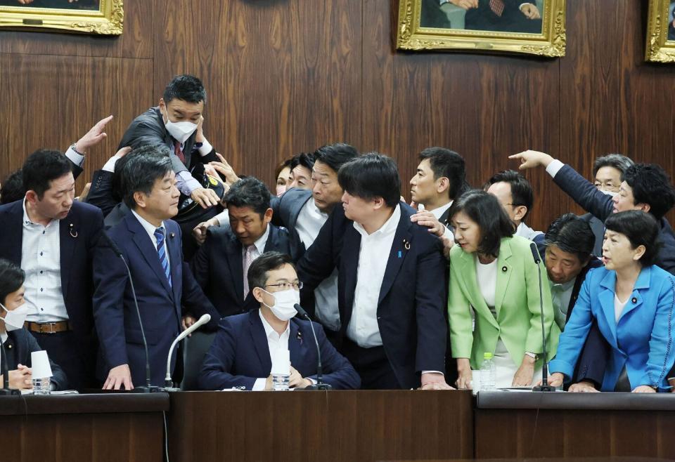 One lawmaker jumps toward another as others look on or try to stop the scuffle