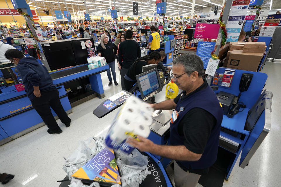 FILE- In this Nov. 9, 2018, file photo Walmart associate Javaid Vohar, right, checks out customers at a Walmart Supercenter in Houston. Walmart Inc. reports earnings Thursday, Nov. 15. (AP Photo/David J. Phillip, File)