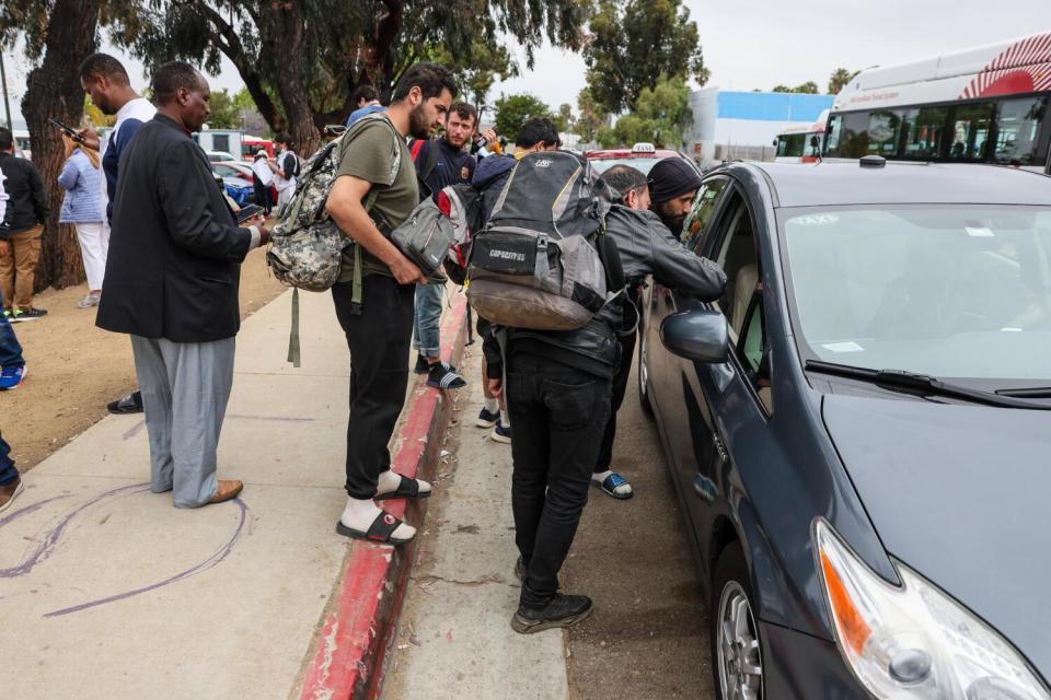 Migrants negotiate a fare with a taxi driver at Iris Avenue Station where they were dropped off by border patrol.