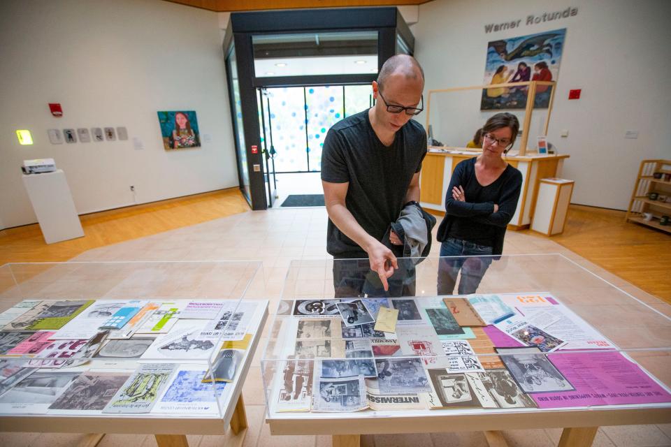 Mark Rospenda, curator of exhibitions and collections, and Brandi Bowman, associate curator, talk about the glass case of old photos and literature from the South Bend Museum of Art's history on display May 25, 2022.