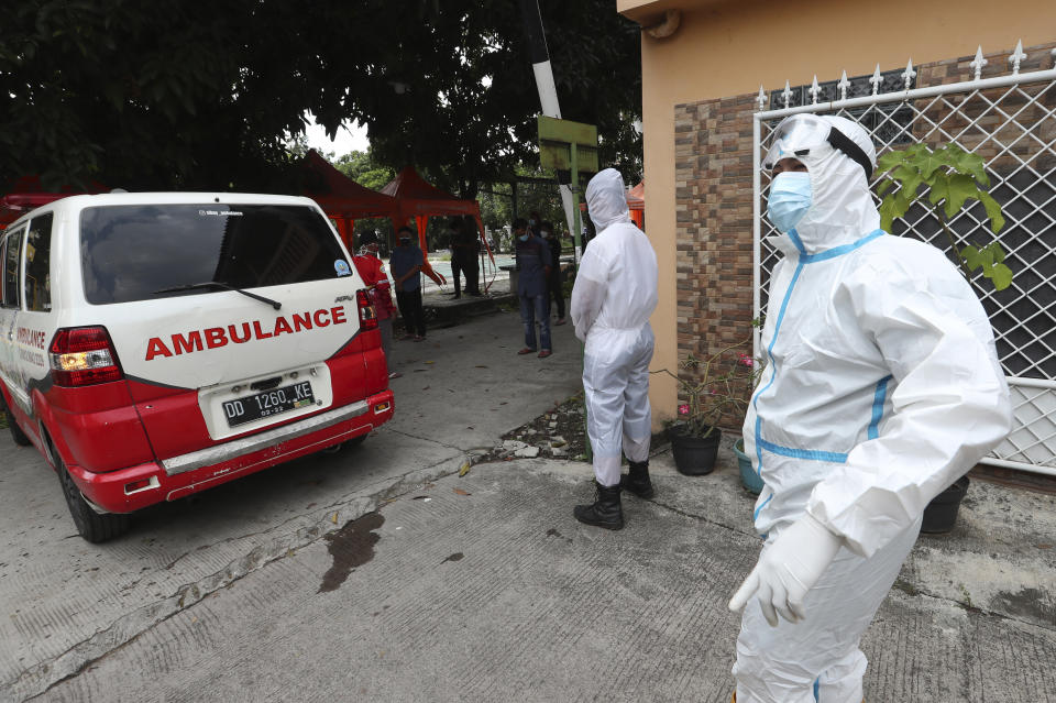 In this July 11, 2021, photo, ambulance drivers wait outside a home of a deceased COVID-19 victim to escort the body to a cemetery for burial in Bekasi on the outskirts of Jakarta, Indonesia, Indonesia surpassed the grim milestone of 100,000 official COVID-19 deaths on Wednesday, Aug. 4, 2021, as the country struggles with its worst pandemic year fueled by the delta variant, with growing concerns that the actual figure could be much higher with people also dying at home. (AP Photo/Achmad Ibrahim)