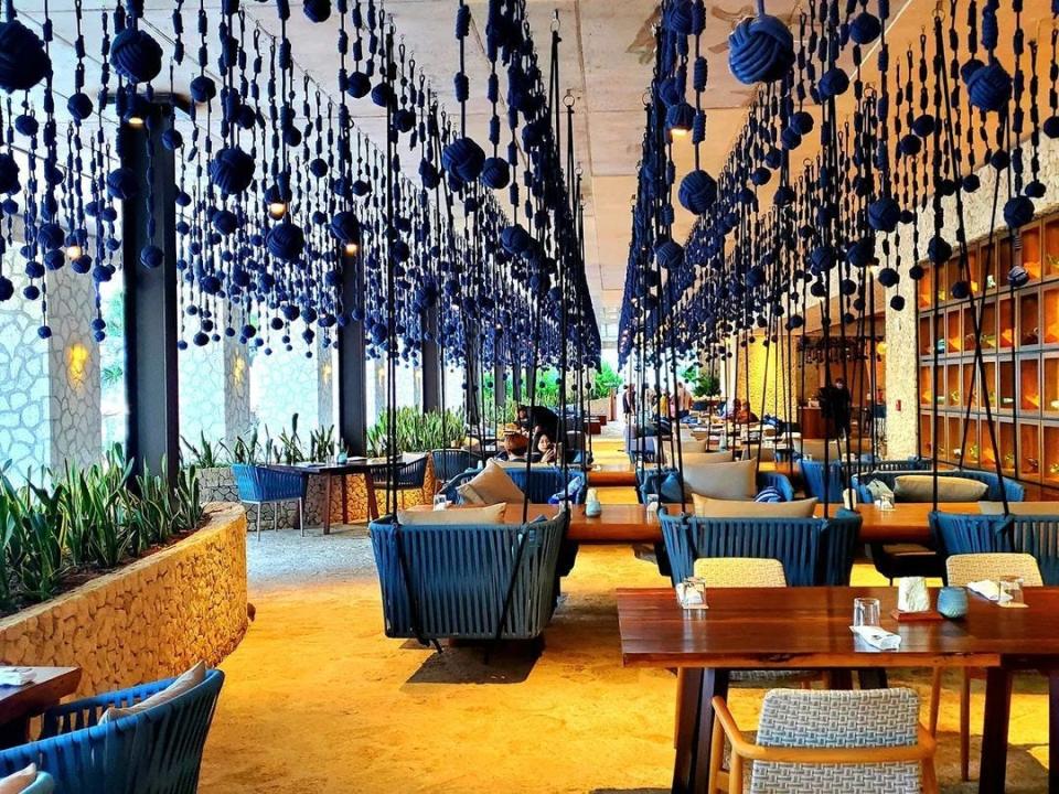 A hotel restaurant with chairs hanging from rope swings.