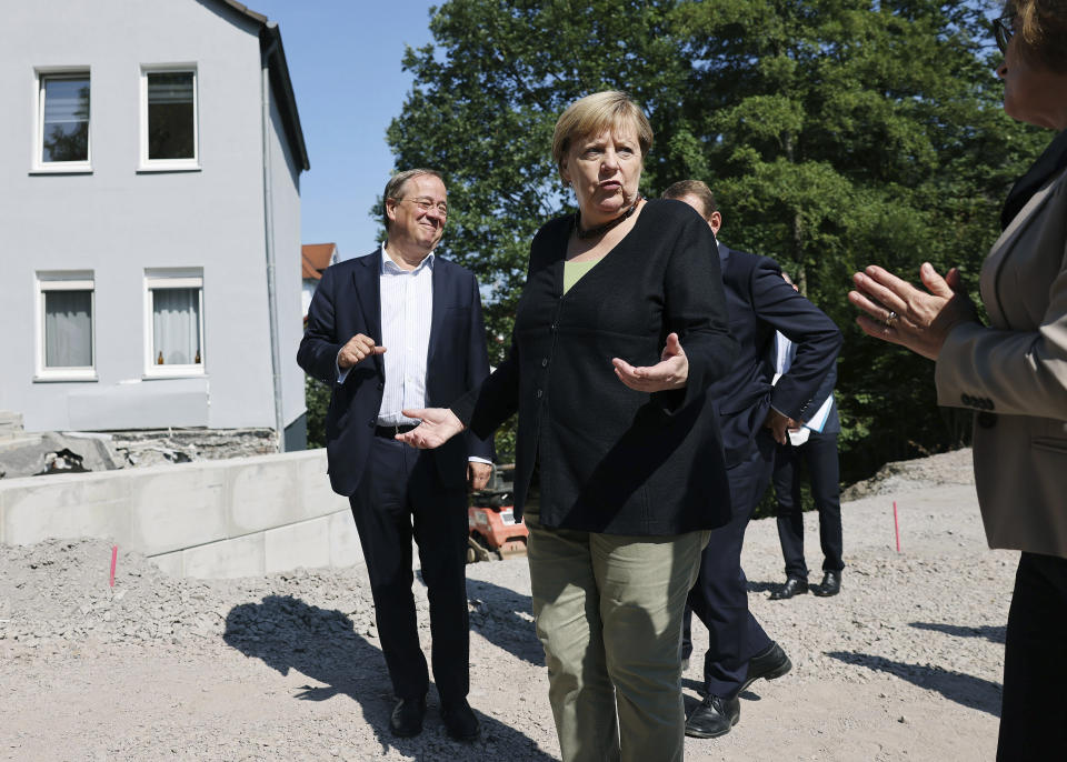 German Chancellor Angela Merkel, centre, with Armin Laschet, left, candidate for chancellor of the CDU/CSU and chairman of the CDU, talk to Petra Beckefeld, right, from the road construction company Strassen, as they vistit areas affected by flooding, in Hagen, Germany, Sunday, Sept. 5, 2021. (Oliver Berg/Pool Photo via AP