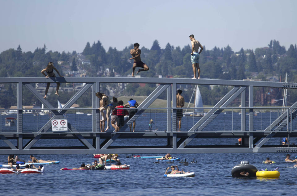 Two people jump from a pedestrian bridge at Lake Union Park into the water during a heat wave hitting the Pacific Northwest, Sunday, June 27, 2021, in Seattle. A day earlier, a record high was set for the day with more record highs expected today and Monday. (AP Photo/John Froschauer)