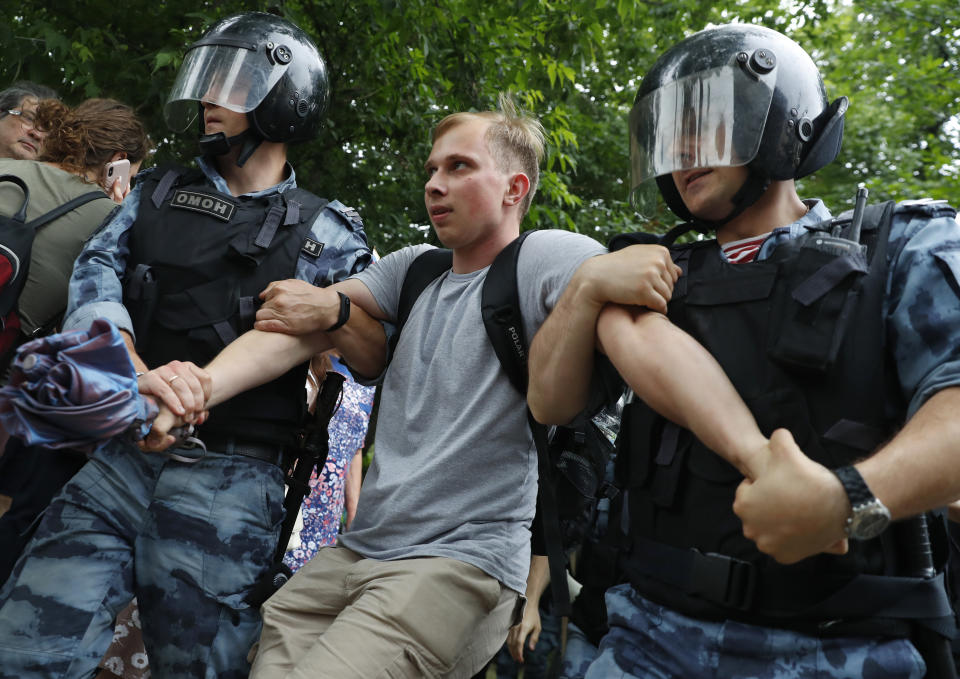 Police officers detain a protester during a march in Moscow, Russia, Wednesday, June 12, 2019. Police and hundreds of demonstrators are facing off in central Moscow at an unauthorized march against police abuse in the wake of the high-profile detention of a Russian journalist. More than 20 demonstrators have been detained, according to monitoring group. (AP Photo/Pavel Golovkin)