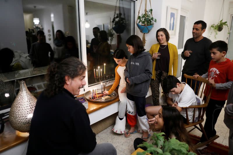 Members of the Ben Shahar family light a hanukkiyah, a candlestick with nine branches that is lit to mark Hanukkah, the 8-day Jewish Festival of Lights, in Moshav Kfar Mordechai, Israel