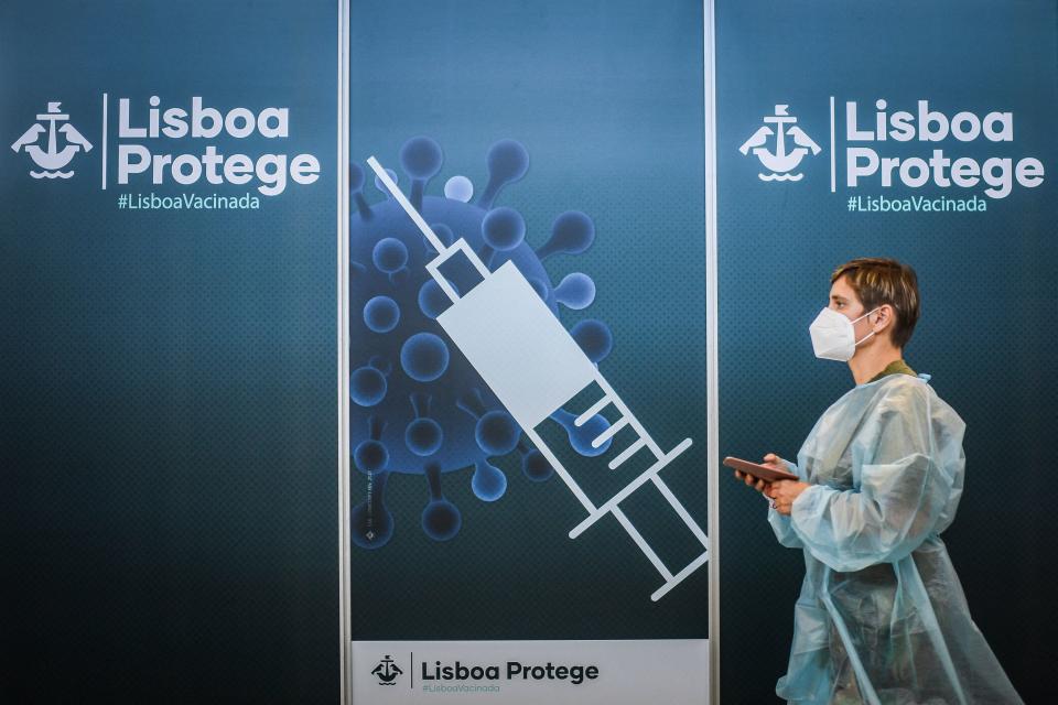 A healthworker walks by a poster at a Covid-19 vaccination center in Lisbon on July 2, 2021. - Nearly half of Portugal's population will be placed under night-time curfews again from Friday as the government seeks to rein in a resurgence in coronavirus infections, primarily due to the more contagious Delta variant. (Photo by PATRICIA DE MELO MOREIRA / AFP) (Photo by PATRICIA DE MELO MOREIRA/AFP via Getty Images)