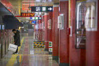 In this Tuesday, Jan. 28, 2020 photo, a man wearing a face mask waits for a train at a nearly empty subway station in Beijing. Fears of a virus outbreak have kept many indoors and at home in China's capital. Cultural landmarks such as the Great Wall and Forbidden City have closed their doors to visitors, nearly deserted shopping malls have reduced their operating hours, and restaurants that remain open draw just a handful of customers.( AP Photo/Mark Schiefelbein)