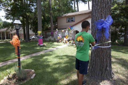 Logan Badoni, 15, ties a ribbon around a tree at a house where six members of the Stay family were murdered in Spring Texas July 12, 2014. REUTERS/Daniel Kramer