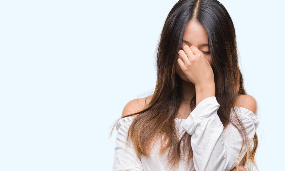 Young asian woman over isolated background tired rubbing nose and eyes feeling fatigue and headache. Stress and frustration concept.