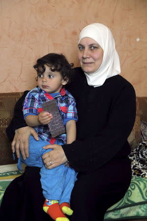 Fawziyeh, a 52-year-old Syrian woman, holds her grandson as she attends an interview with Reuters at her house in a small town south of Beirut, Lebanon April 15, 2015. REUTERS/Aziz Taher