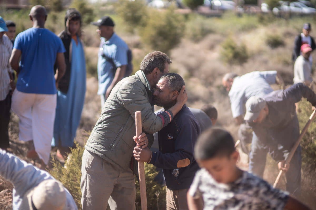 People comfort each other while digging graves for victims of the earthquake, in Ouargane village, near Marrakech (AP)