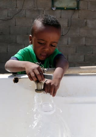 A Libyan child displaced from the town of Tawergha fills containers with water at a displaced camp in Benghazi